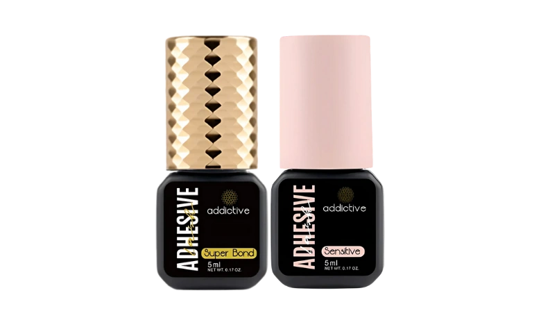 Δύο μπουκαλάκια επαγγελματικής κόλλας extensions της Addictive Lashes: Super Bond με χρυσό καπάκι για μέγιστη διάρκεια και Sensitive με ροζ καπάκι για ευαίσθητα μάτια.