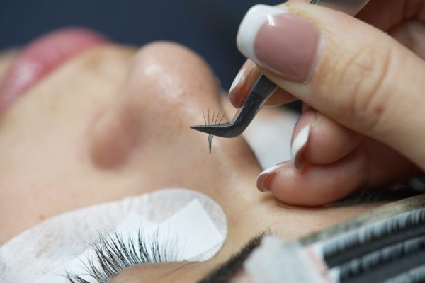 Λαβίδα που έχει ένα τουφάκι από βλεφαρίδες πριν τοποθετήθει στις φυσικές βλεφαρίδες