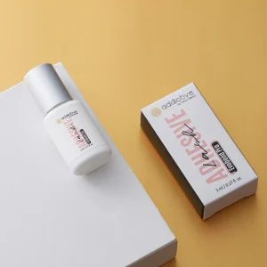 Λευκό μπουκαλάκι με ασημί καπάκι της επαγγελματικής κόλλας βλεφαρίδων Evobond Pro της Addictive Lashes, φωτογραφημένο δίπλα στο κουτί συσκευασίας του. Διακρίνεται η ονομασία του προϊόντος και η χωρητικότητα 5ml.