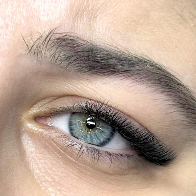 Κοντινή λήψη ματιού με εφαρμογή extensions τεχνικής Half Set. Διακρίνεται η τοποθέτηση που δίνει έμφαση από το κέντρο του ματιού προς τα έξω, προσφέροντας άμεσο lifting εφέ και "γατίσιο" βλέμμα (cat eye) με λιγότερο χρόνο εφαρμογής.